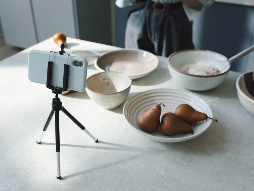 Cozy kitchen scene capturing baking preparations with smartphone tripod setup.
